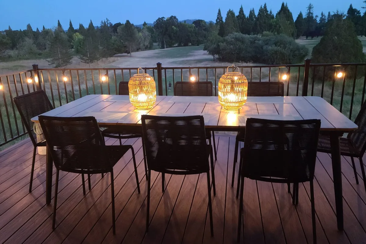 A welcoming exterior seating area with a wooden table and lanterns, overlooking the scenic landscape. Comfortable chairs invite relaxation, making it the perfect spot for sunset viewing, outdoor dining, or simply enjoying the sounds and sights of nearby wildlife.