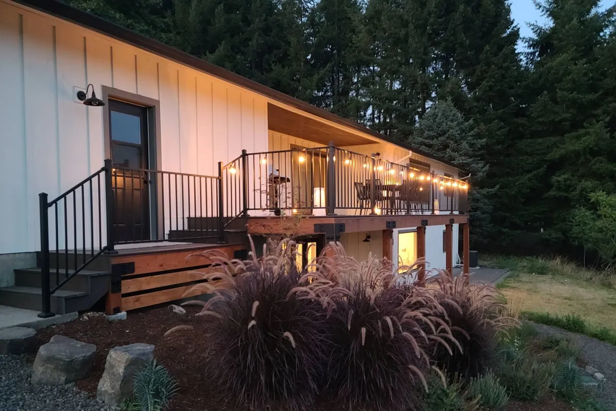 A cozy deck setup with string lights, comfortable seating, and lush landscaping, perfect for relaxing after a round of golf. The scene suggests evening gatherings, post-game refreshments, and a seamless indoor-outdoor lifestyle overlooking the course.