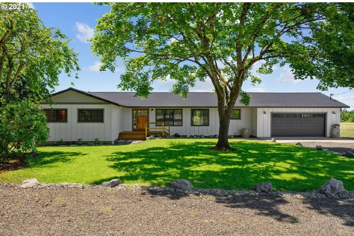 The image displays the main entrance of Jade’s View Estate, framed by a large, mature tree and surrounded by manicured lawns. The home’s inviting façade and peaceful greenery set a welcoming tone for arriving guests, suggesting a tranquil yet distinguished retreat environment.