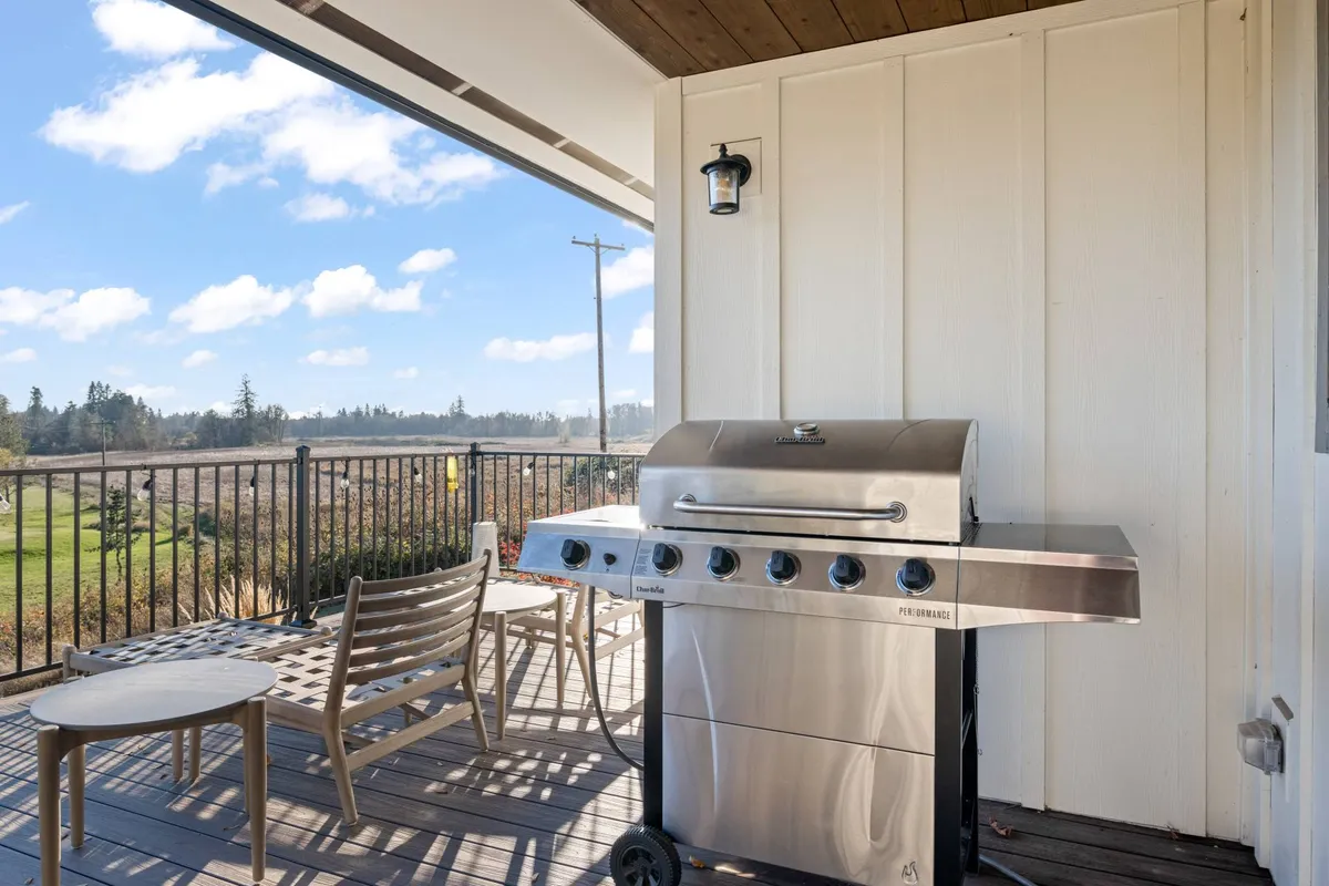 An exterior deck area featuring a grill, comfortable seating, and a wide view of the lush landscape beyond. The setup suggests an ideal spot for relaxed gatherings, al fresco dining, and unwinding after local adventures.