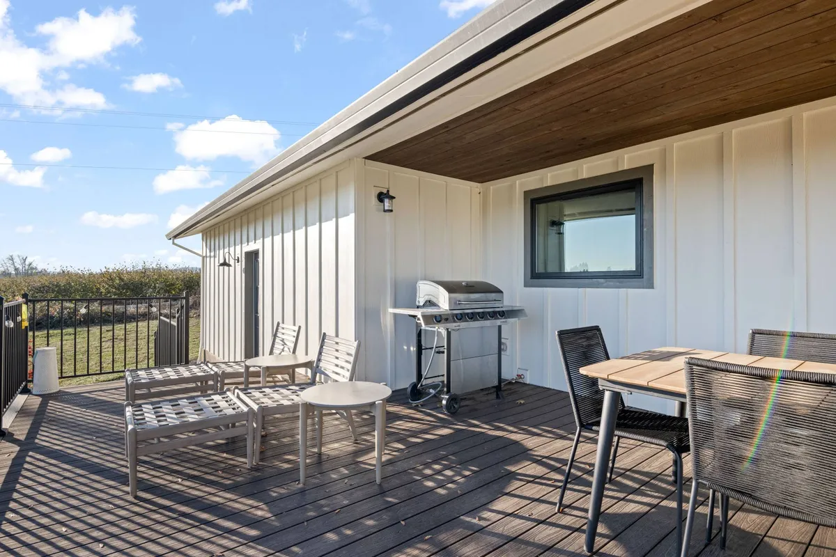 An outdoor seating area with a grill and table, perfect for alfresco gatherings. The space is designed for both casual relaxation and social interaction, surrounded by natural beauty and ideal for team networking or winding down after a day of meetings.